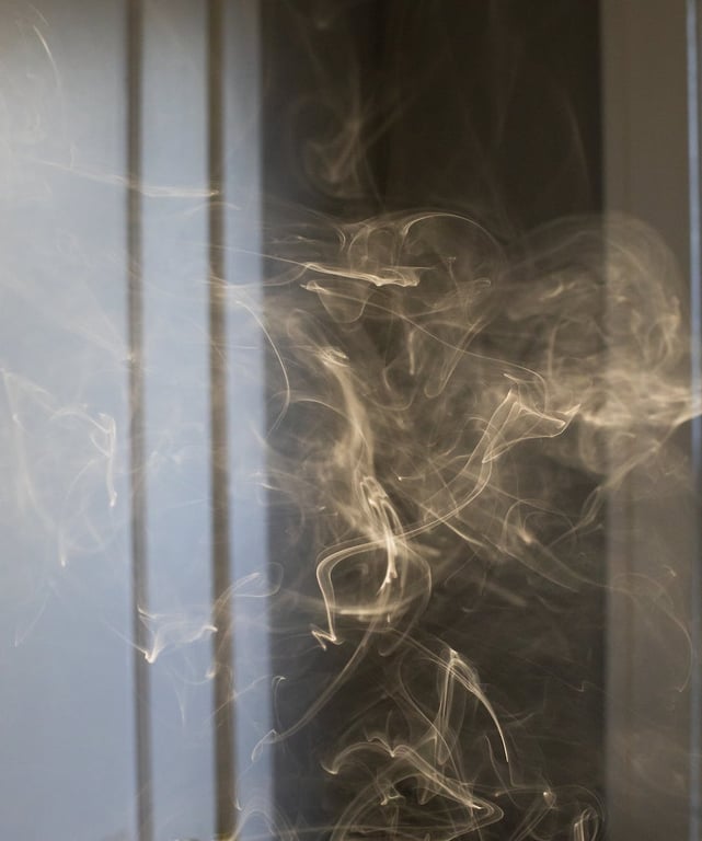 Swirling thick smoke of cigarette forming chaotic figures in dark room in apartment